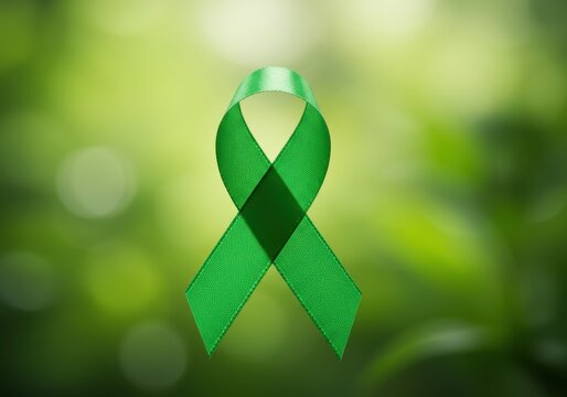 A green ribbon against a blurred green background symbolizing support and awareness for a cause