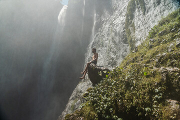 Chico sobre roca en cascada de Tumpak Sewu, Java, Indonesia