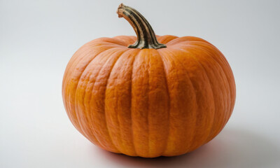 Obraz premium A small orange pumpkin sits alone on a white surface, perfect for fall decorations or food styling