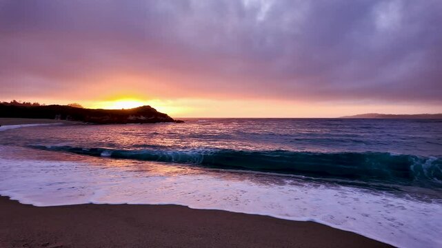 View of the waves rolling in during colorful sunset in California at Monastery Beach.