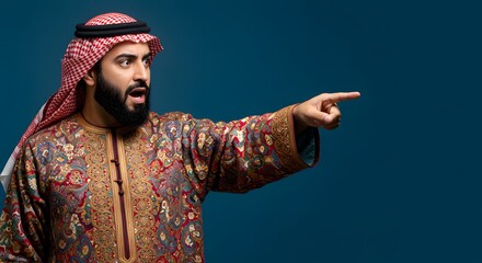 A surprised arab man in traditional attire points his finger to the right against blue.