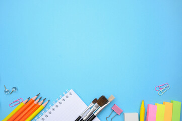 Colorful stationery, brushes, and notebooks arranged on pastel blue background. Ideal for school banners, creative ads, and online courses.