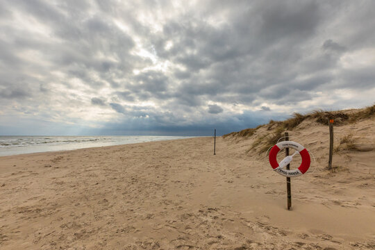 Deserted beach with lifebuoy under dramatic cloudy sky in Sandhammaren, Sweden.