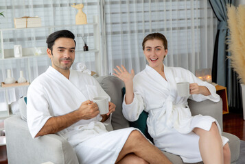 Obraz premium Beauty or body treatment spa salon vacation lifestyle concept with couple wearing bathrobe relaxing with drinks in luxurious hotel spa or resort room. Vacation and leisure relaxation. Quiescent