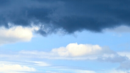 Obraz premium White and dark fluffy clouds and blue sky. Stormy day. Cloudy in a sunny day. Dramatic nature sky. Rainy season.