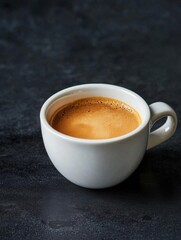 Close-up of a white coffee cup with a handle on a black textured surface. the cup is filled with a dark brown liquid, which appears to be freshly brewed coffee.
