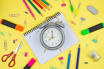 A Colorful Collection of Stationery and a Clock Displayed on a Bright Yellow Background
