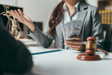 Lawyer holding dollar banknotes and gesturing with hand while explaining something to client in law firm office