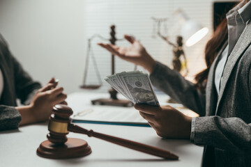 Lawyer holding and showing dollar banknotes to client in office during consultation meeting, legal,...