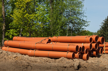 Stack of Orange PVC Drainage Pipes at Outdoor Construction Site