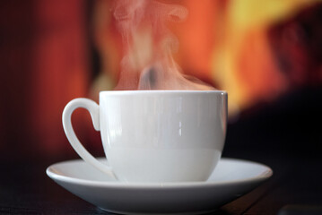 A steaming white coffee cup resting on a cozy background creates a comforting visual experience