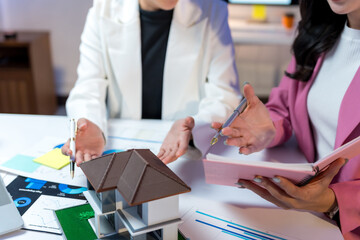 Real estate agent showing house model to client during a meeting, discussing mortgage and property purchase agreement