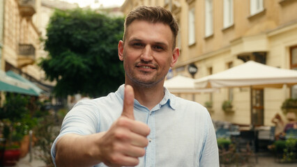 Happy smiling Caucasian man business guy male businessman satisfied tourist holiday travel outdoors showing thumb up gesture recommend respect approval sign like hand shopper buyer in city outside