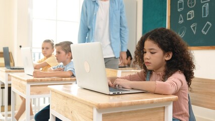 American girl learning about coding engineering prompt while diverse students sitting at STEM...