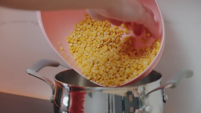 A person rinses yellow split peas in a pink colander, allowing water to wash away impurities.