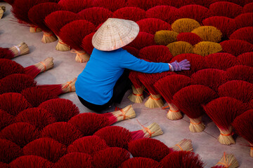 Vietnamese female worker arranging red incense sticks in village factory