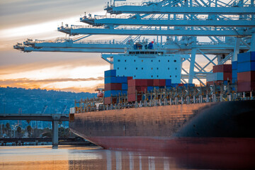 Large container ship docked next to unloading terminal at dusk
