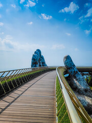 Empty Golden Bridge in Ba Na hills, Da Nang, Vietnam on a sunny day. Lifted by two giant concrete hands. Iconic world famous bridge in the mountains