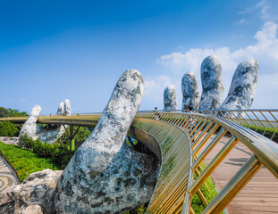 Golden Bridge in Ba Na hills, Da Nang, Vietnam on a sunny day. Lifted by two giant concrete hands. Iconic world famous bridge in the mountains