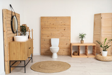 Interior of restroom with sink, mirror and toilet bowl