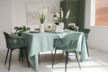 Interior of light room with served dining table and white Gladiolus flowers