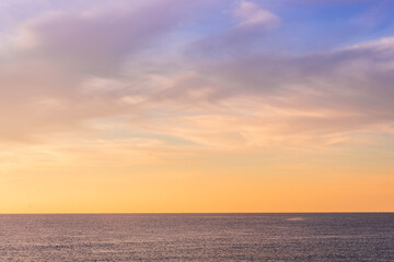 scenic sunrise or sunset above sea water with beautiful ocean vawes , nice golden evening clouds above horizon and awesome blue sky