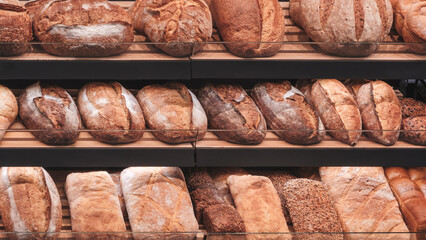 A display of breads with a variety of shapes and sizes. The breads are arranged on shelves and are ready to be purchased.