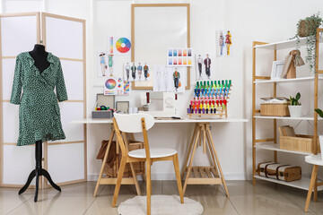 Interior of light atelier with tailor's workplace, shelf unit and mannequin