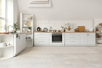 Interior of kitchen with white counters, shelf units and utensils