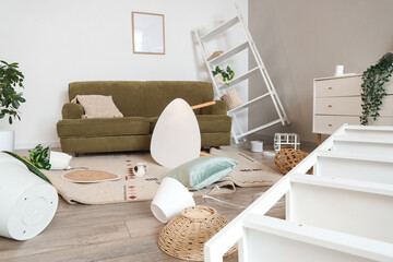 Interior of messy living room with sofa and fallen things after earthquake