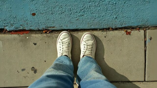 POV photo of canvas shoes on city sidewalk