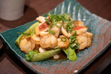 Butter soy scallops and calamari stir fry garnished with chopped scallions