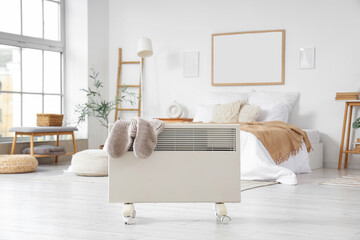 Electric convector heater with socks in bedroom interior