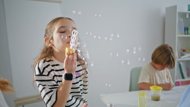 Carefree schoolgirl blowing soap bubbles school break closeup. Children resting