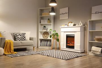 Interior of living room with fireplace, sofa and glowing lamps in evening