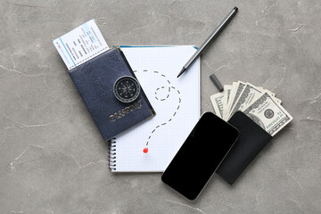 Notebook with drawn route, compass, blank mobile phone and money on grunge background. Itinerary concept