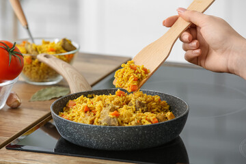 Woman frying pilaf in kitchen, closeup