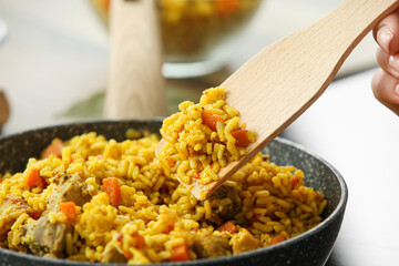 Woman frying pilaf in kitchen, closeup