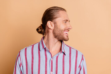 Handsome man with a groomed appearance smiling sideways in a striped shirt against a beige background