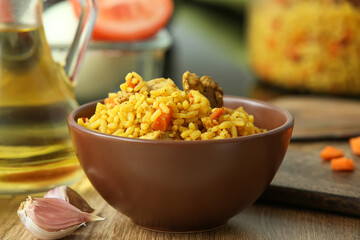 Bowl of tasty pilaf on table in kitchen, closeup