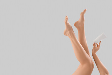Legs of young woman with cream tube on white background