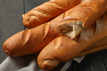 Tray with fresh baguettes on black wooden background, closeup