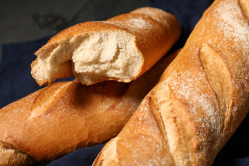 Fresh baguettes on black wooden background, closeup