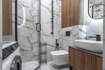 A stylish bathroom featuring a glass shower enclosure, modern fixtures, wood accents, and marble...