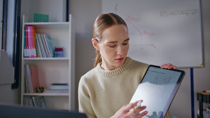 Young teacher explaining online lesson pointing tablet at class room closeup
