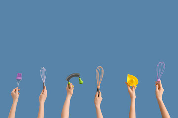 Female hands with kitchen utensils on blue background