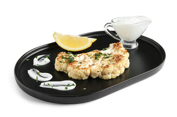 Plate of grilled cauliflower steak with lemon and sauce on white background