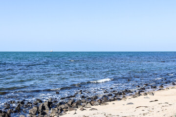 sea and beach with waves and distant shipping vessel