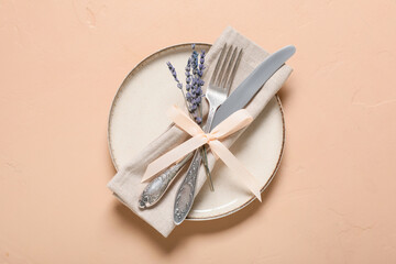 Beautiful table setting with silver cutlery and lavender flowers on beige background