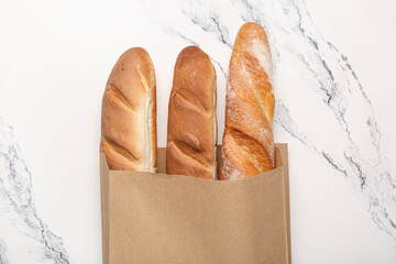 Paper bag with fresh baguettes on white background